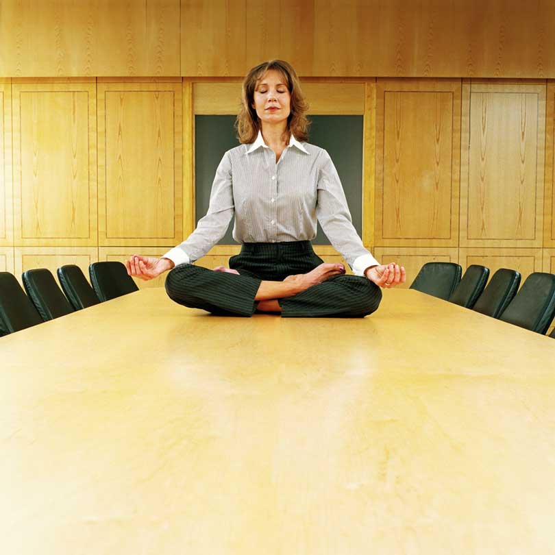 Women sitting in yoga pose on desk.